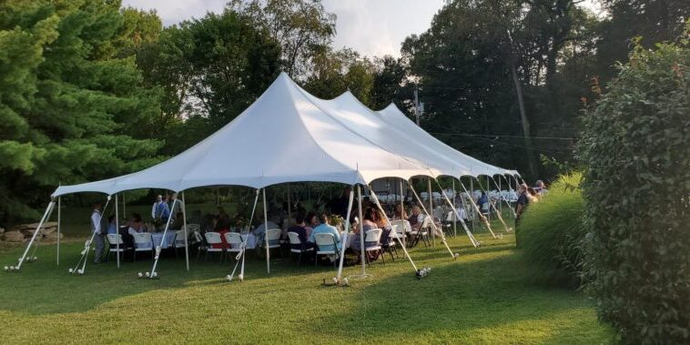 Outdoor gathering under large white tent.