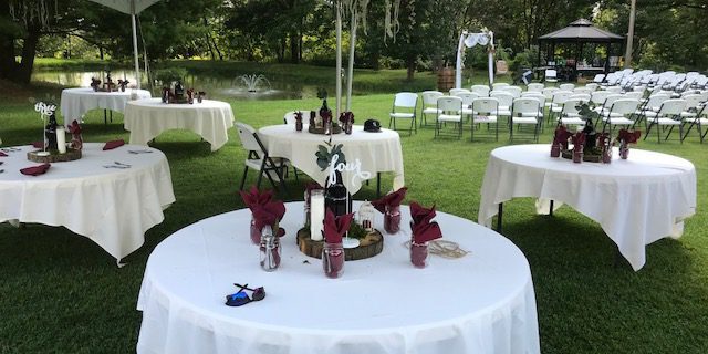 Outdoor wedding reception with decorated round tables.