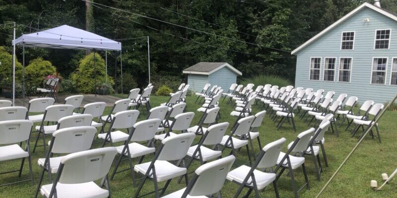 Outdoor event setup with white folding chairs.