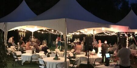 Outdoor evening event under illuminated tents.