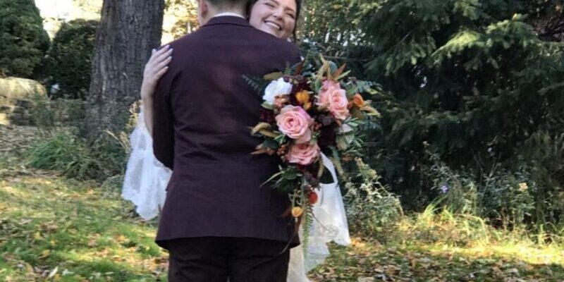 Bride and groom hugging in forest setting.