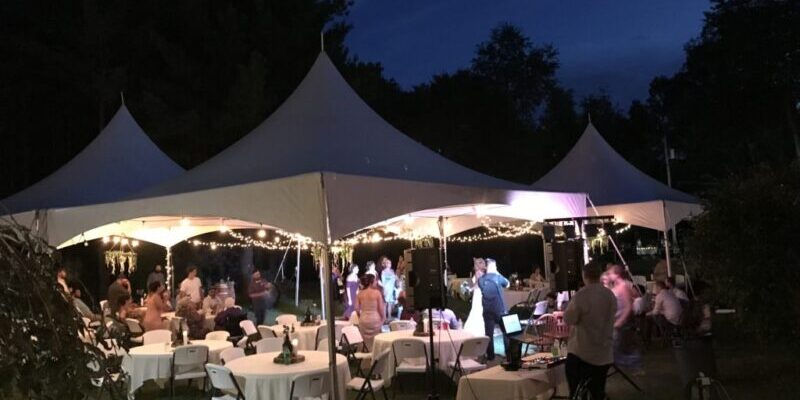 Outdoor evening event under illuminated tents.