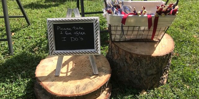 Wedding favors displayed on tree stumps outdoors.