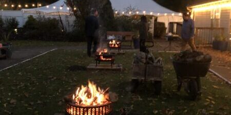 Outdoor fire pits with tent and lights.