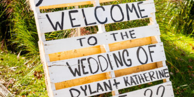 Wedding welcome sign on wooden pallet outdoors.
