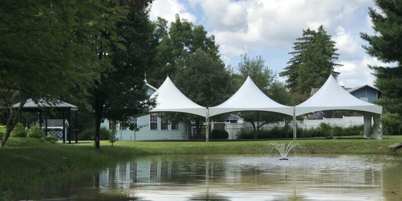 Pond with white tents and trees nearby.
